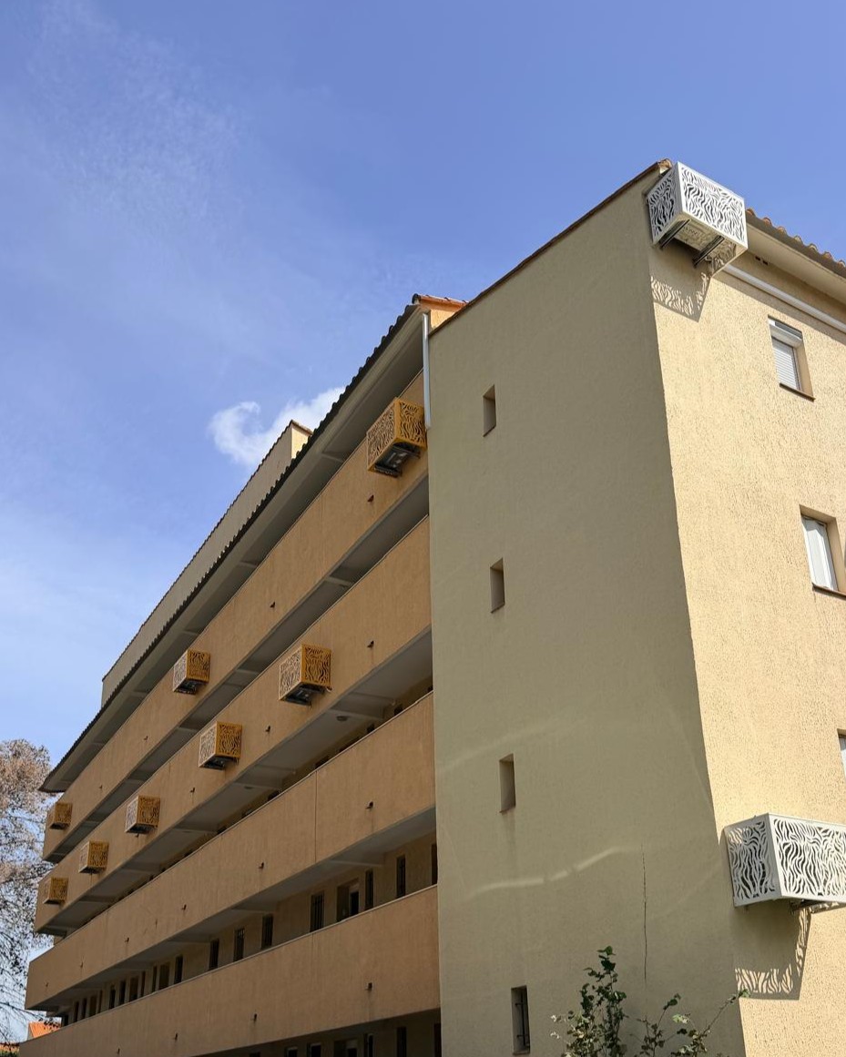 Rangée de cache-clim décoratifs installés sur plusieurs étages d'une résidence
