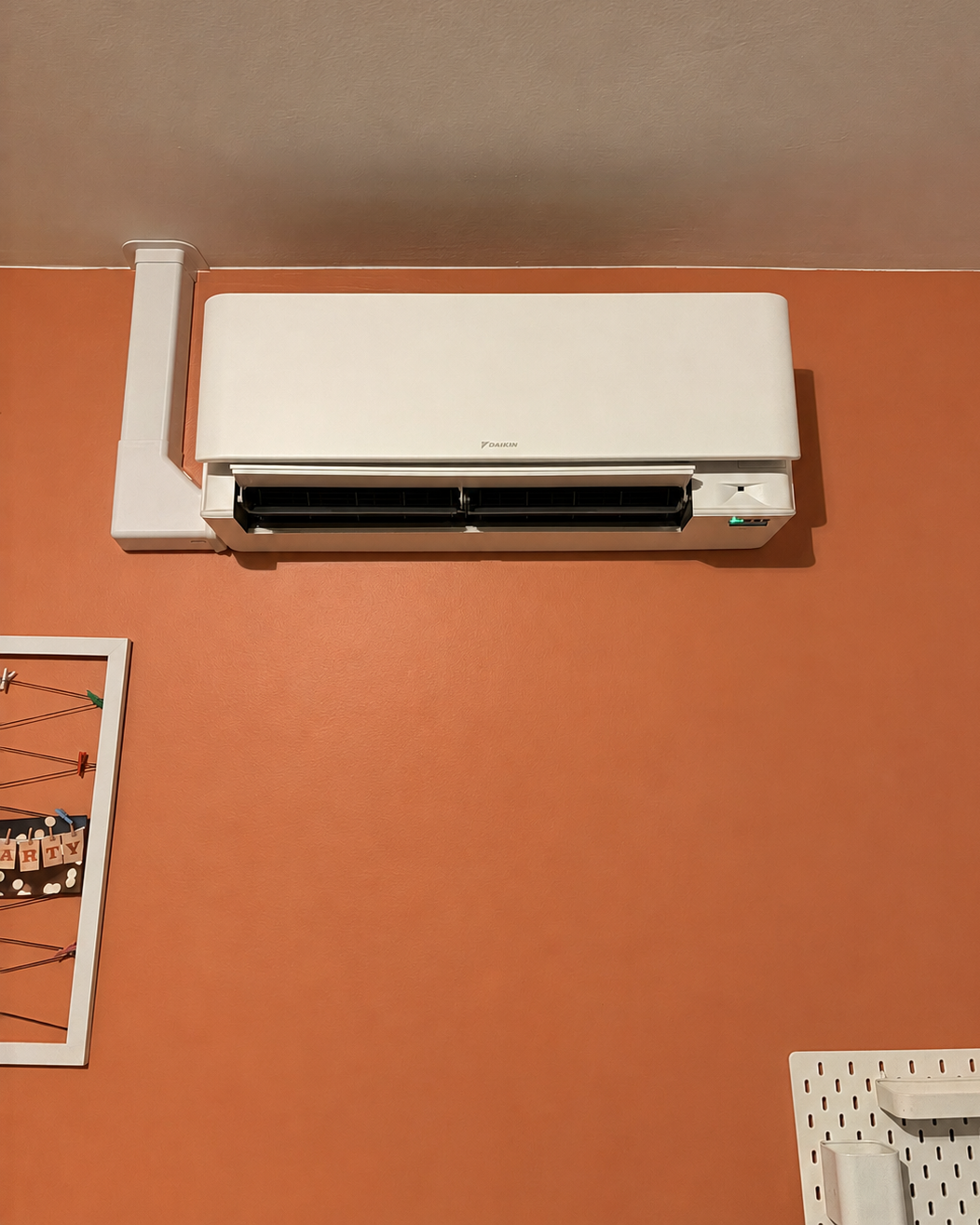 Unité murale Daikin Stylish blanche installée sur un mur orange dans une chambre d'enfant