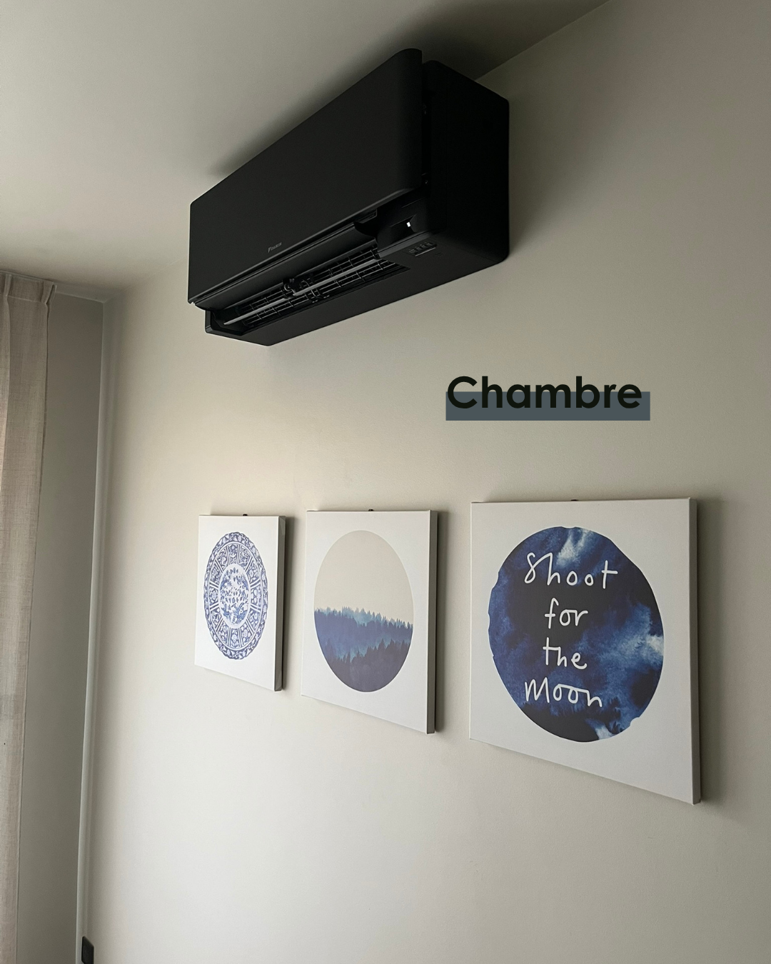 Unité murale de climatisation réversible noire installée au-dessus d'une porte dans une chambre
