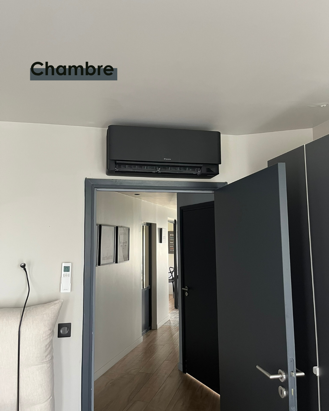 Unité murale de climatisation réversible Daikin noire installée en hauteur dans une chambre