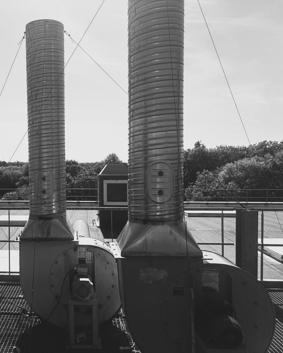 Cheminées d'extraction jumelles avec ventilateurs centrifuges sur toiture industrielle