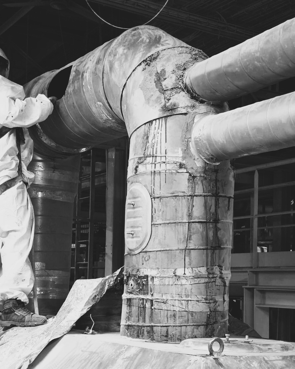 Réseau d'extraction industriel corrodé avant maintenance industrielle, technicien en combinaison blanche