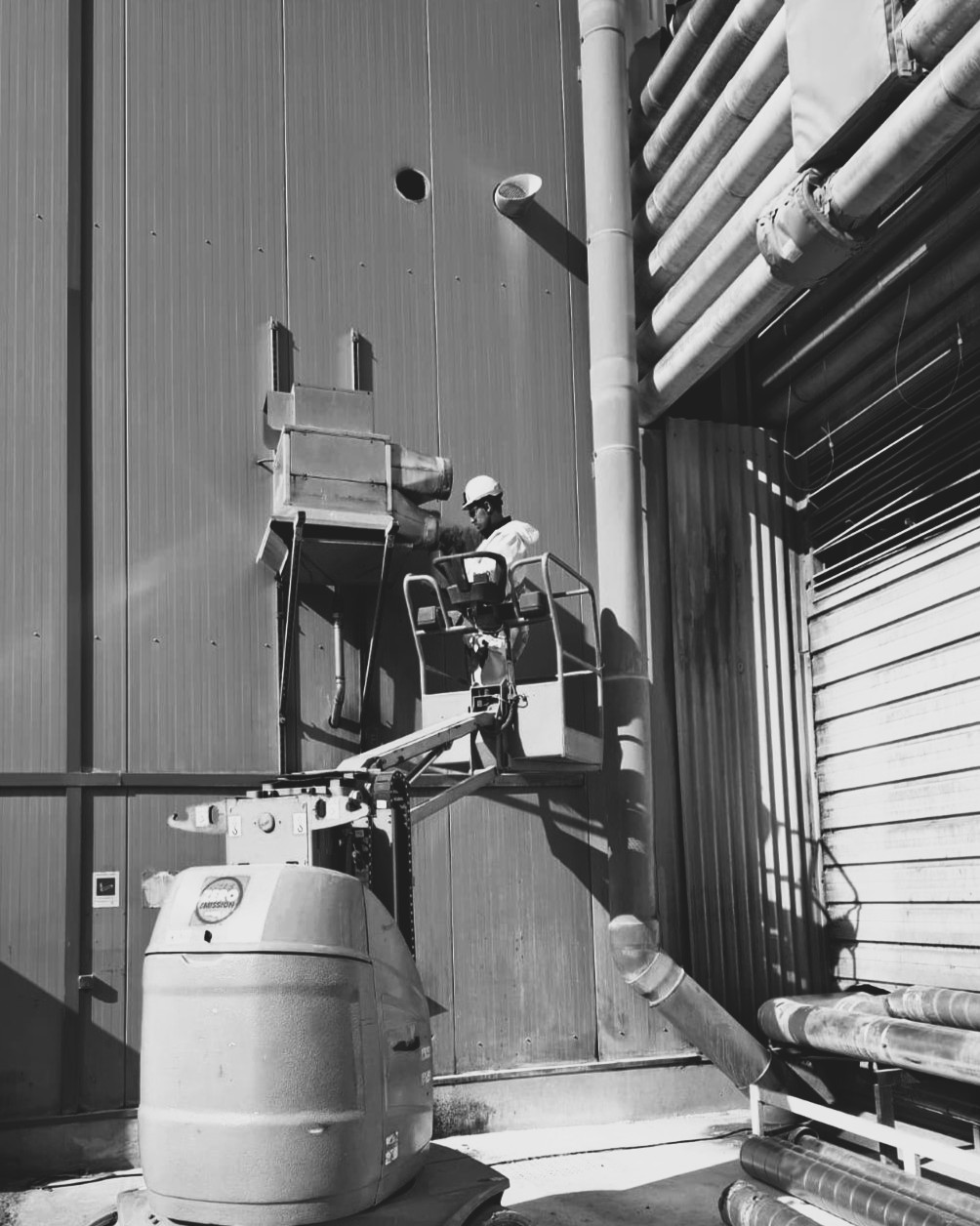 Technicien sur nacelle élévatrice intervenant sur un dépoussiéreur en façade d'usine