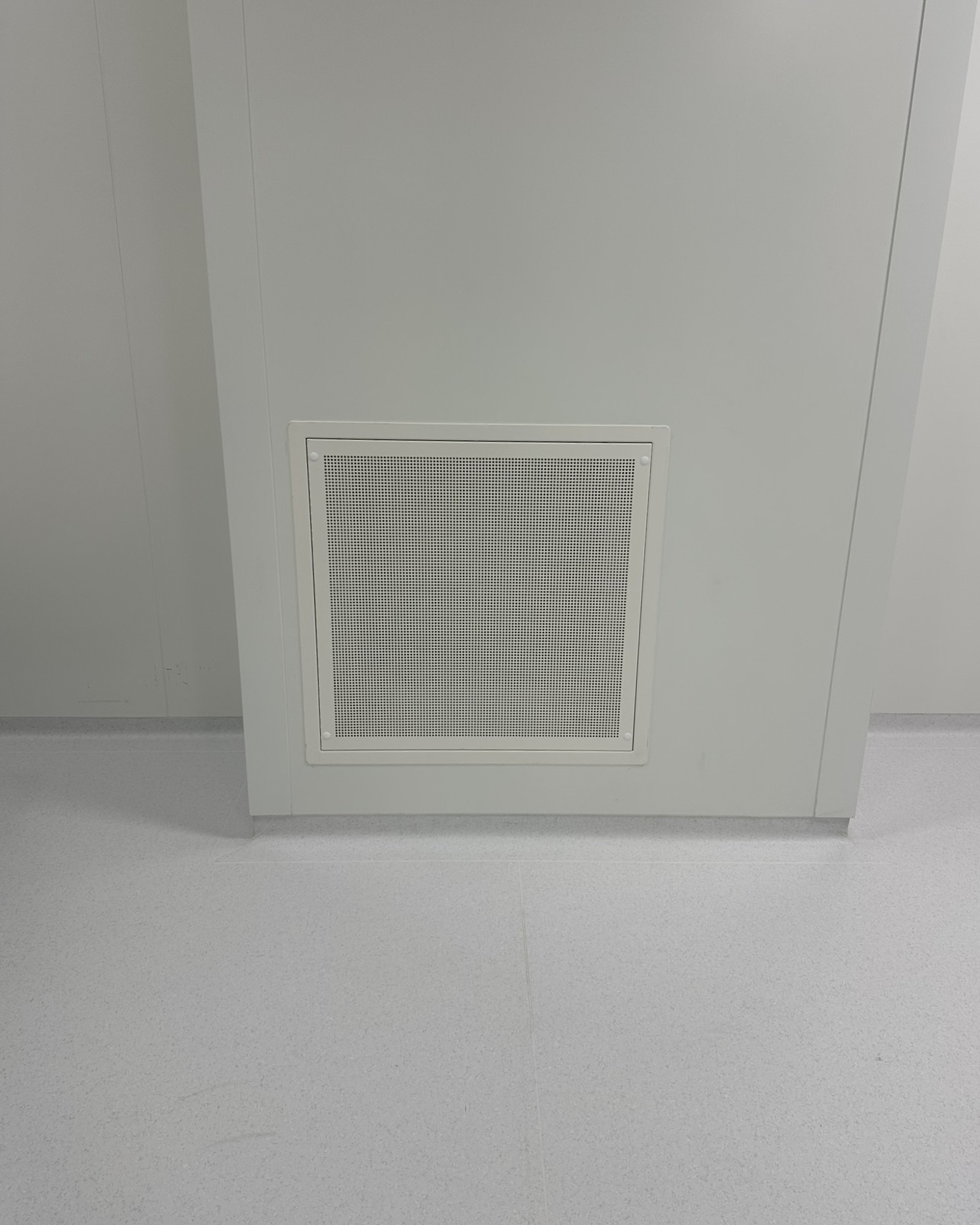 Grille de diffusion d'air perforée installée en bas de mur dans une salle propre