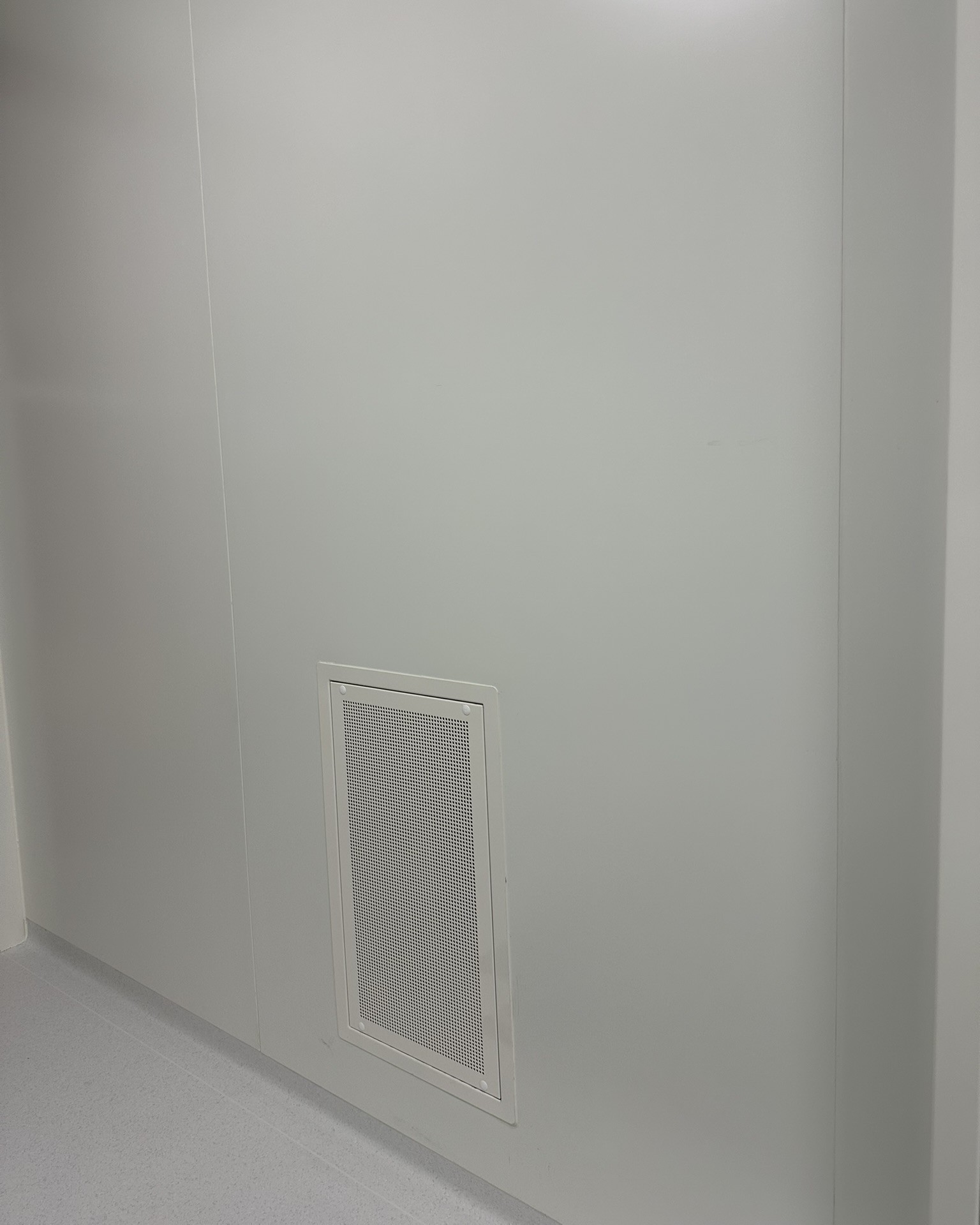 Grille de ventilation murale discrète installée dans une salle propre pharmaceutique